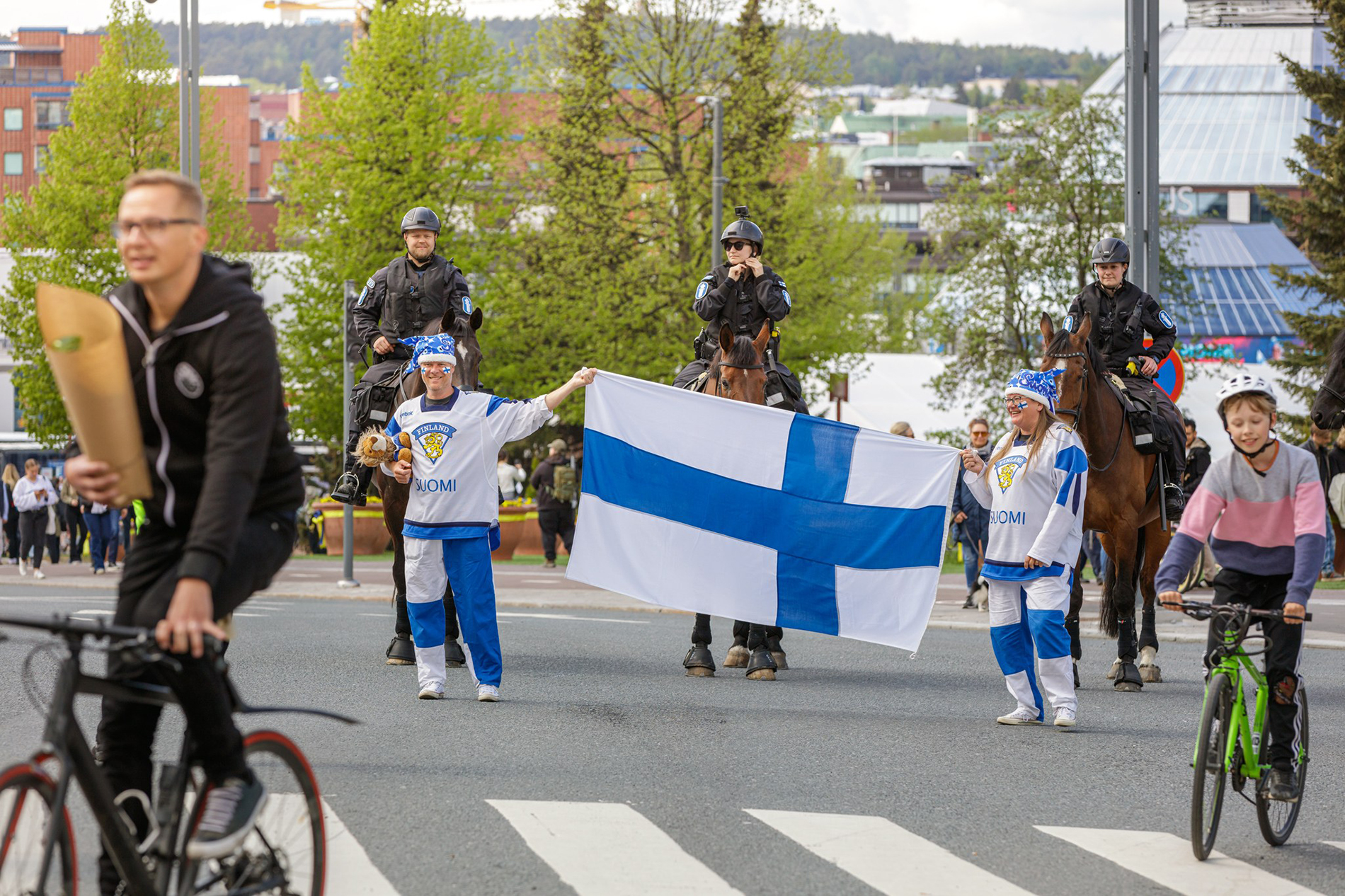 Kiekkofanit pitelevät Suomen lippua takanaan ratsupoliisit.