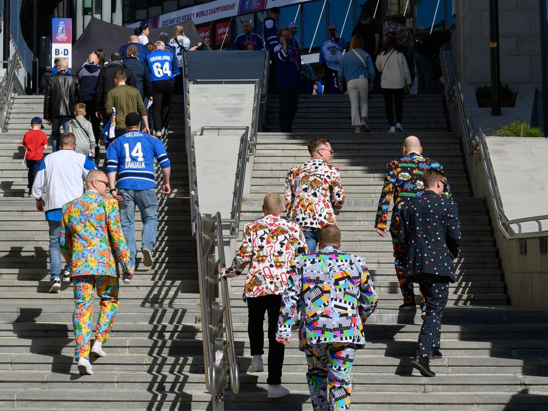 A group of friends runnig upstair to the Nokia Arena wearing colourful suits.