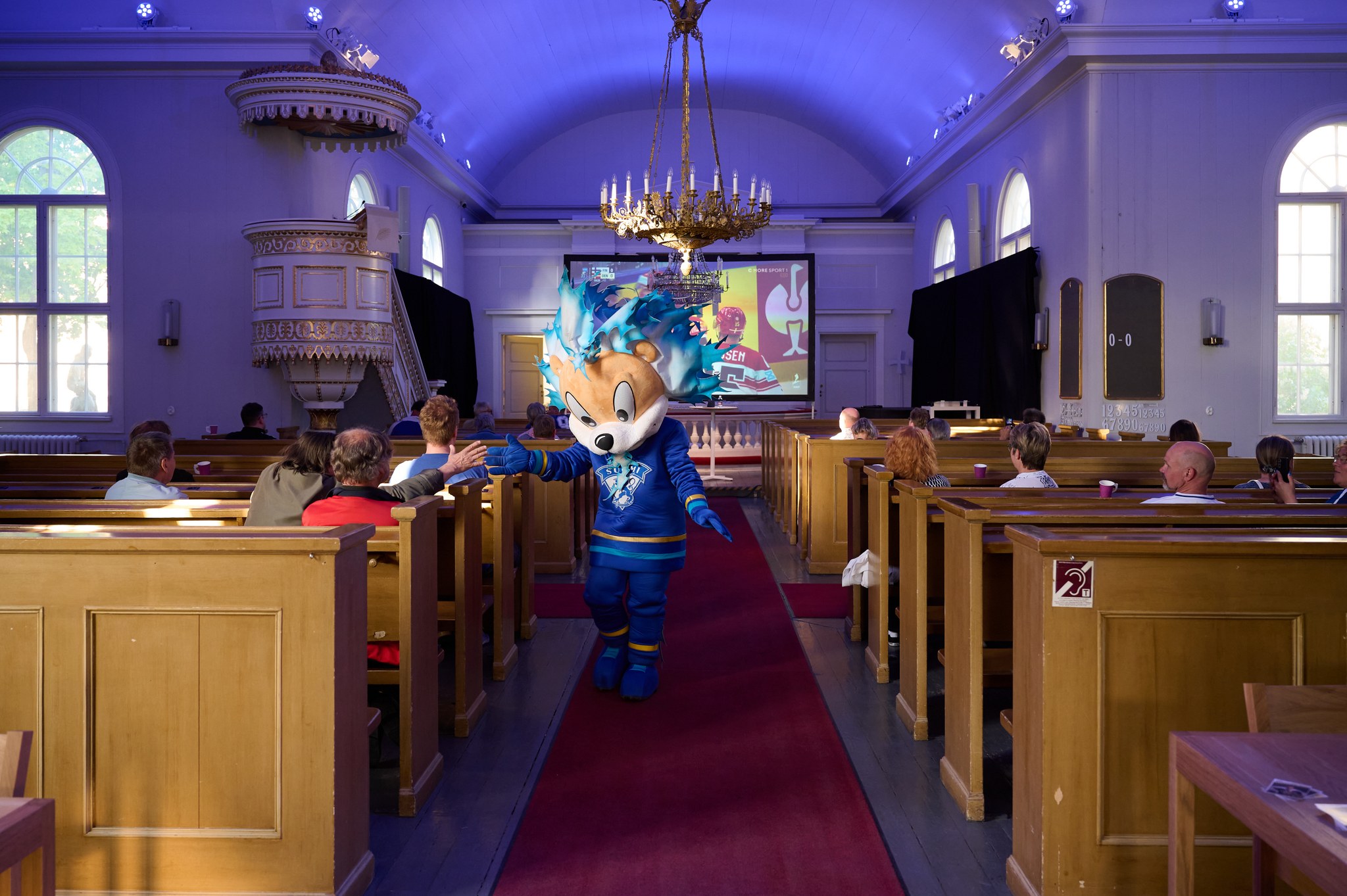 Finnish hockey mascot in church where they are screening a game.