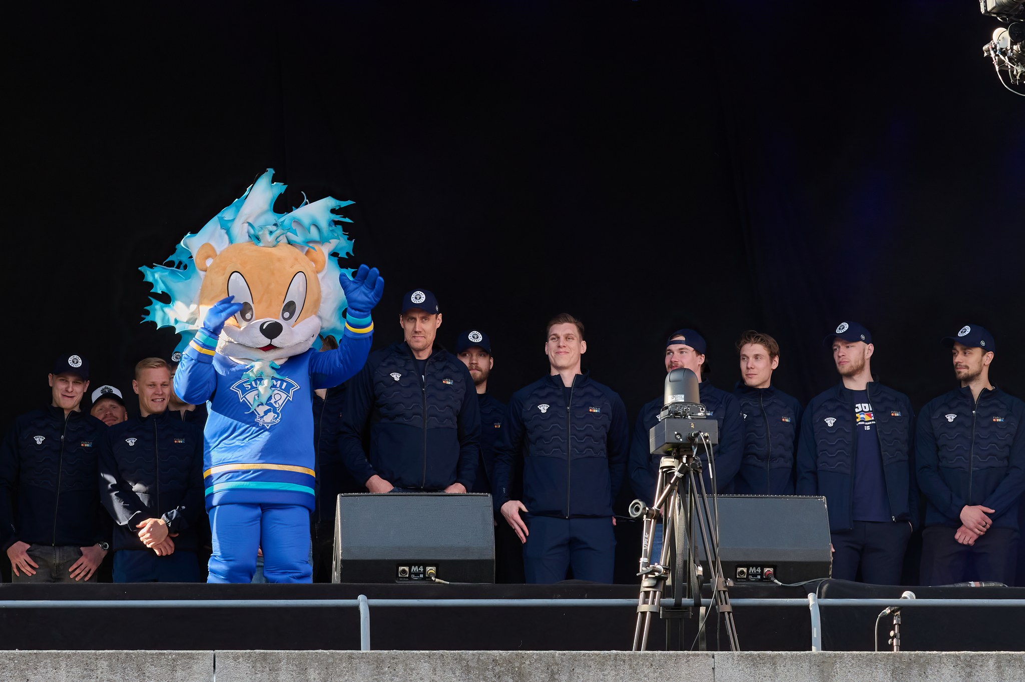 Suomen jääkiekkomaajoukkue lavalla Leijona-maskotin kanssa.