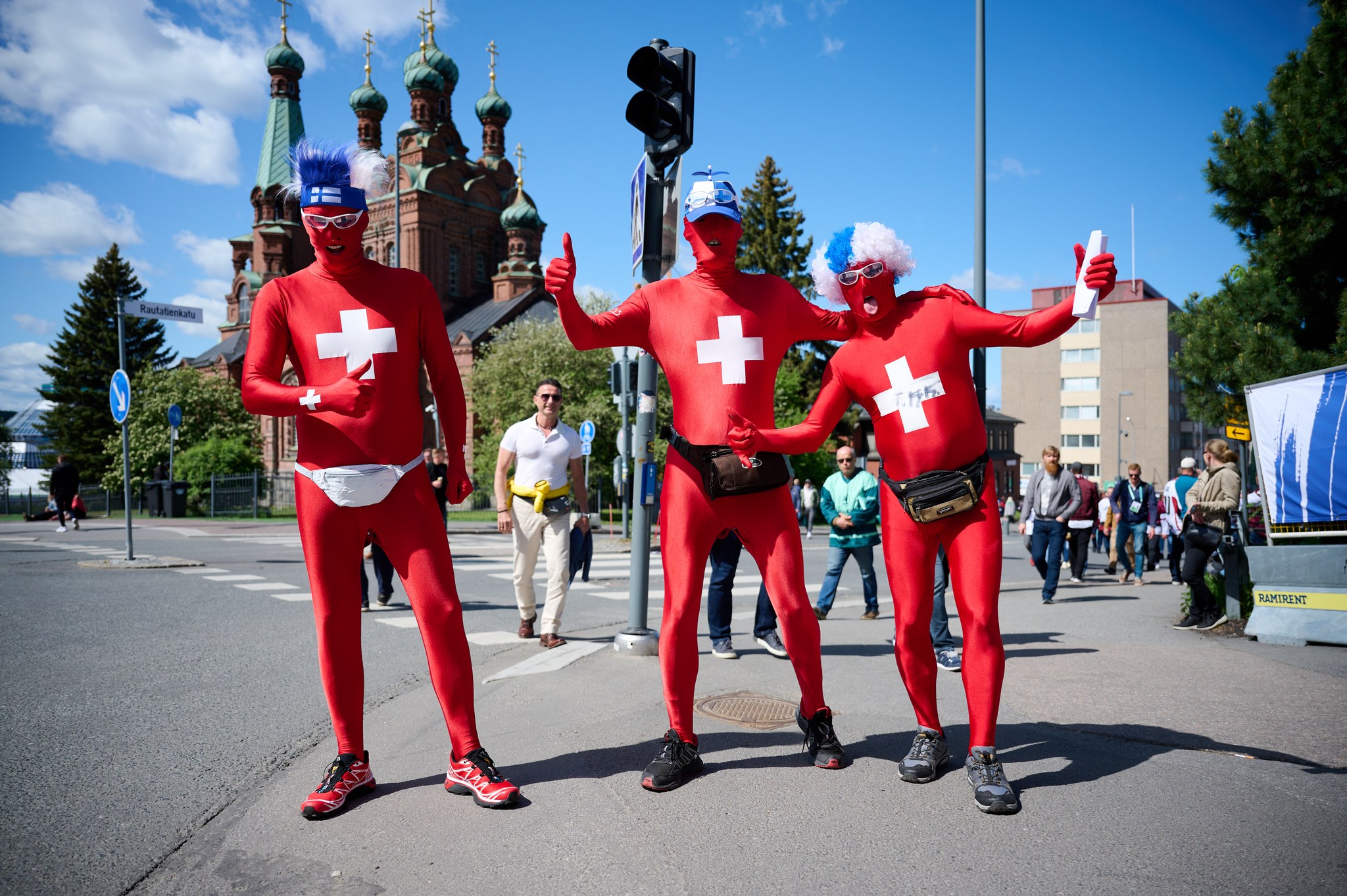 Sveitsin lippua muistuttaviin kokovartaloasuihin pukeutuneet jääkiekkofanit poseeraavat.